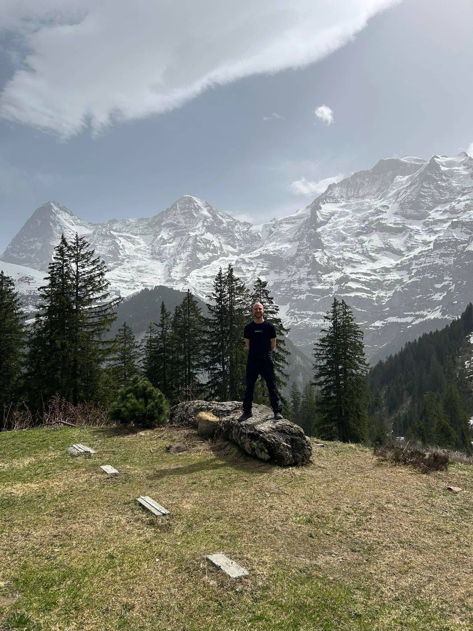 Josef Braun steht auf einem Felsen vor verschneiten Bergen