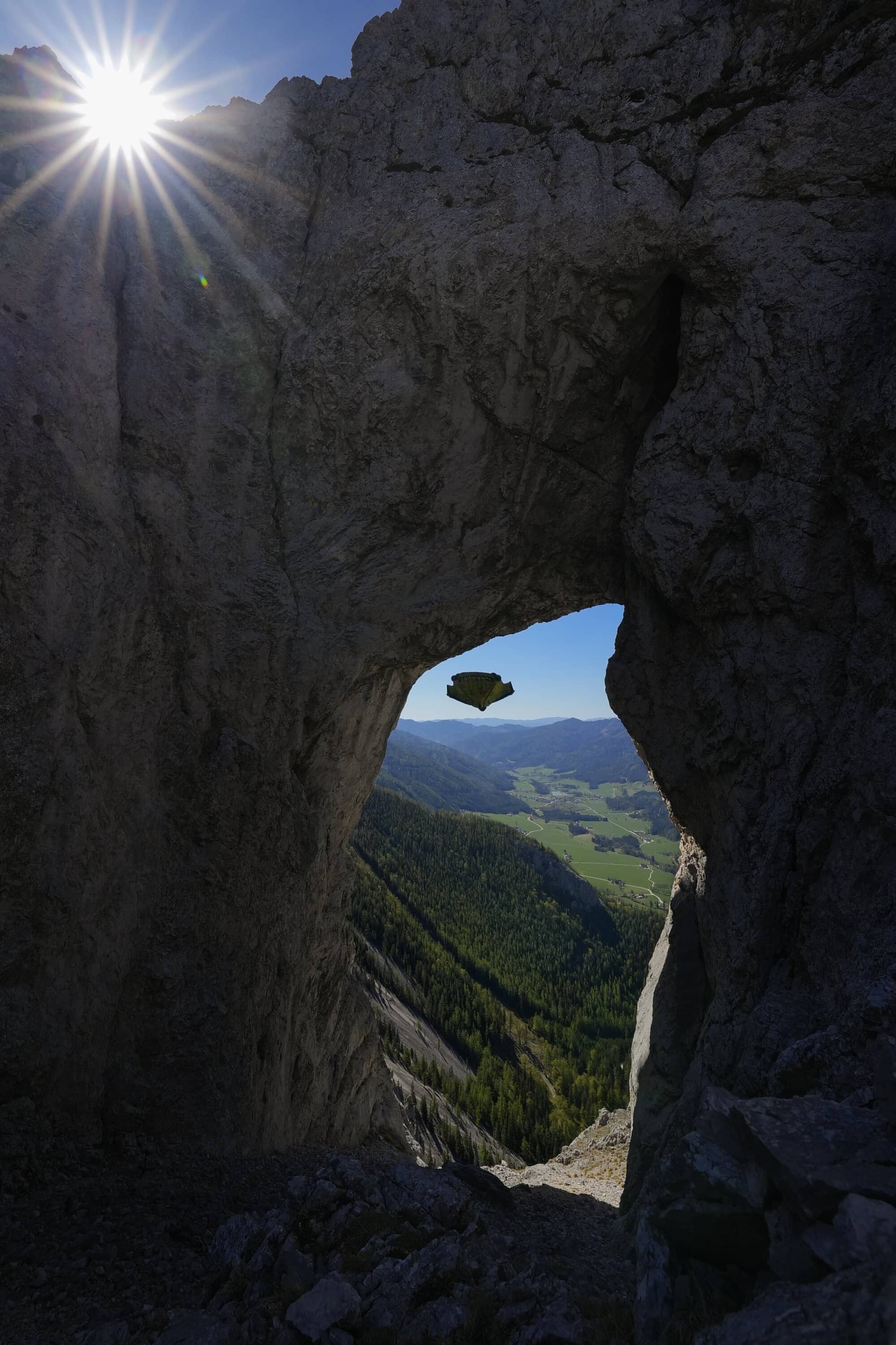 Wingsuit-Flieger durch einen natürlichen Felsbogen gesehen