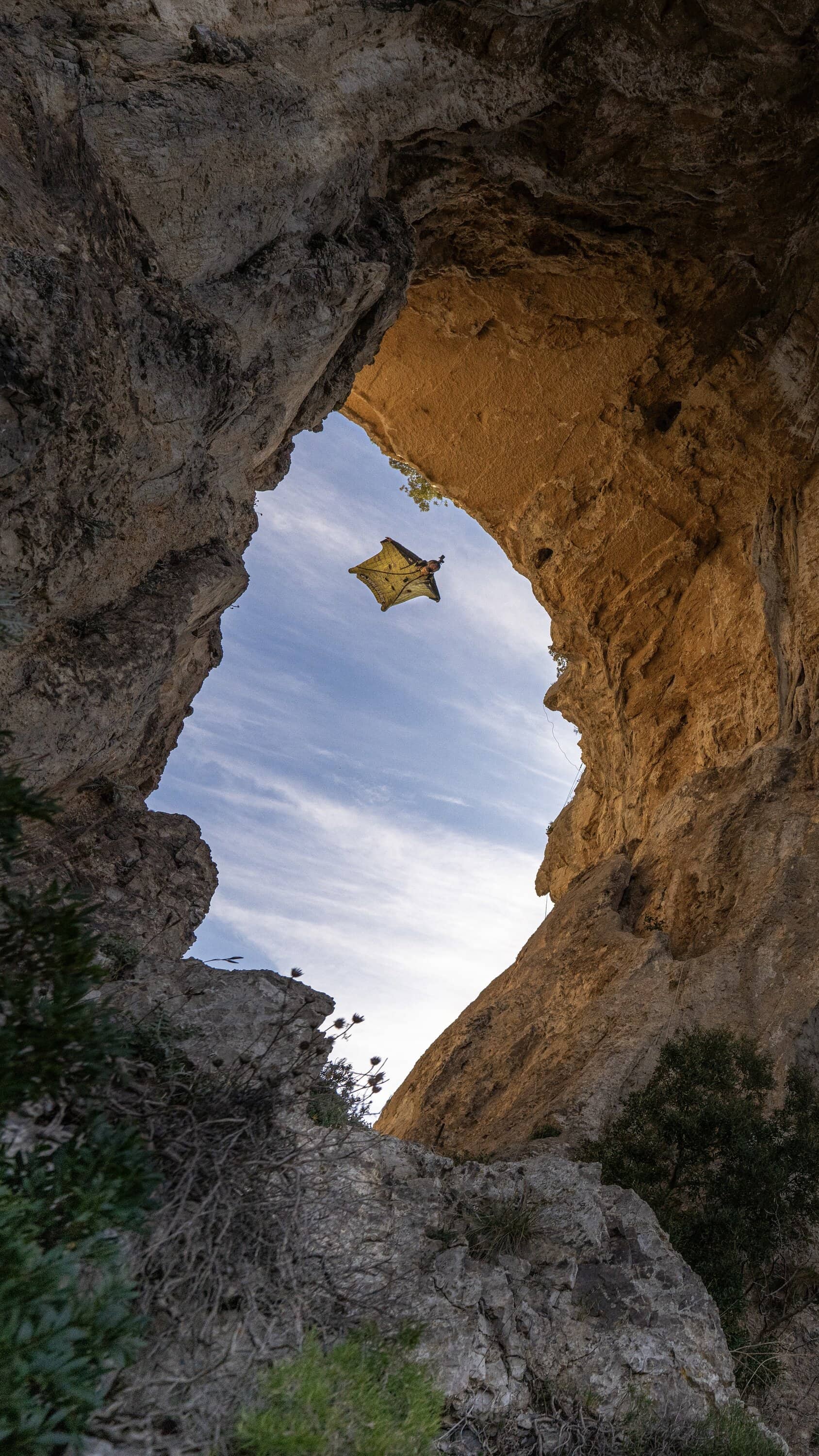 Wingsuit-Flieger fliegt unter einer Felsöffnung hindurch
