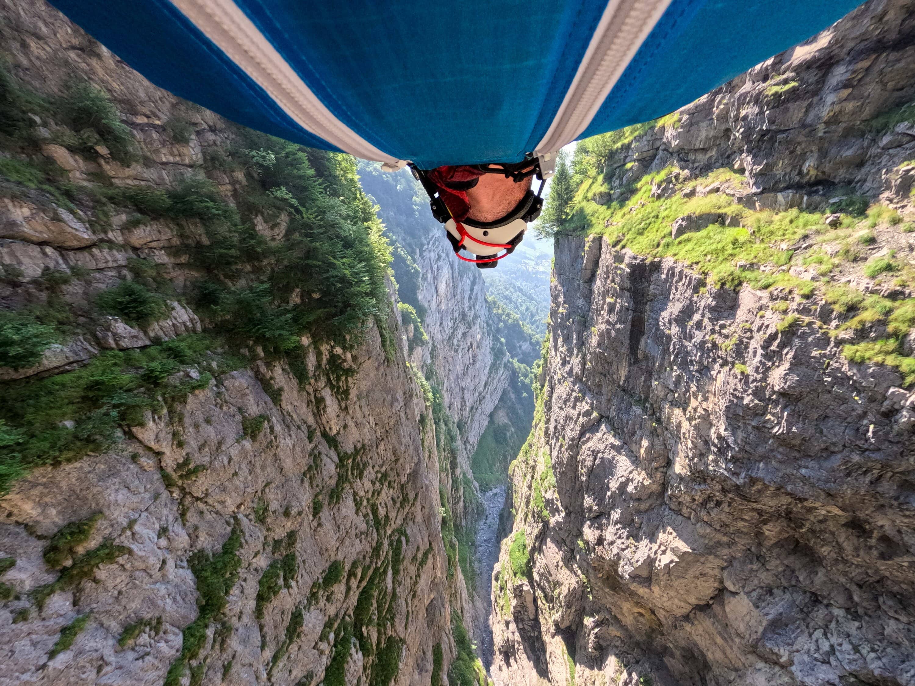 Wingsuit-Pilot fliegt kopfüber zwischen steilen Schluchtwänden