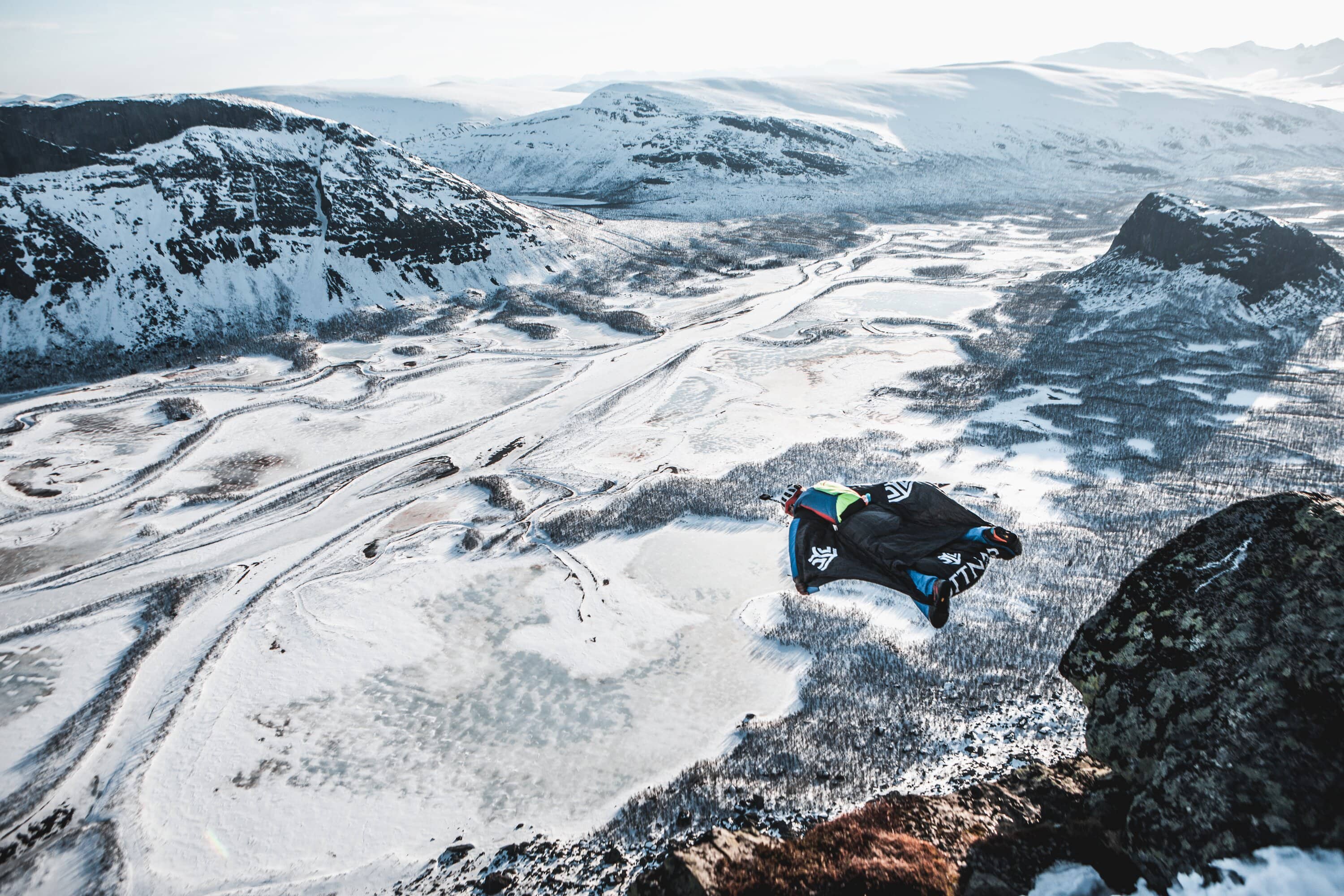 Wingsuit-Flieger über einem verschneiten Bergplateau