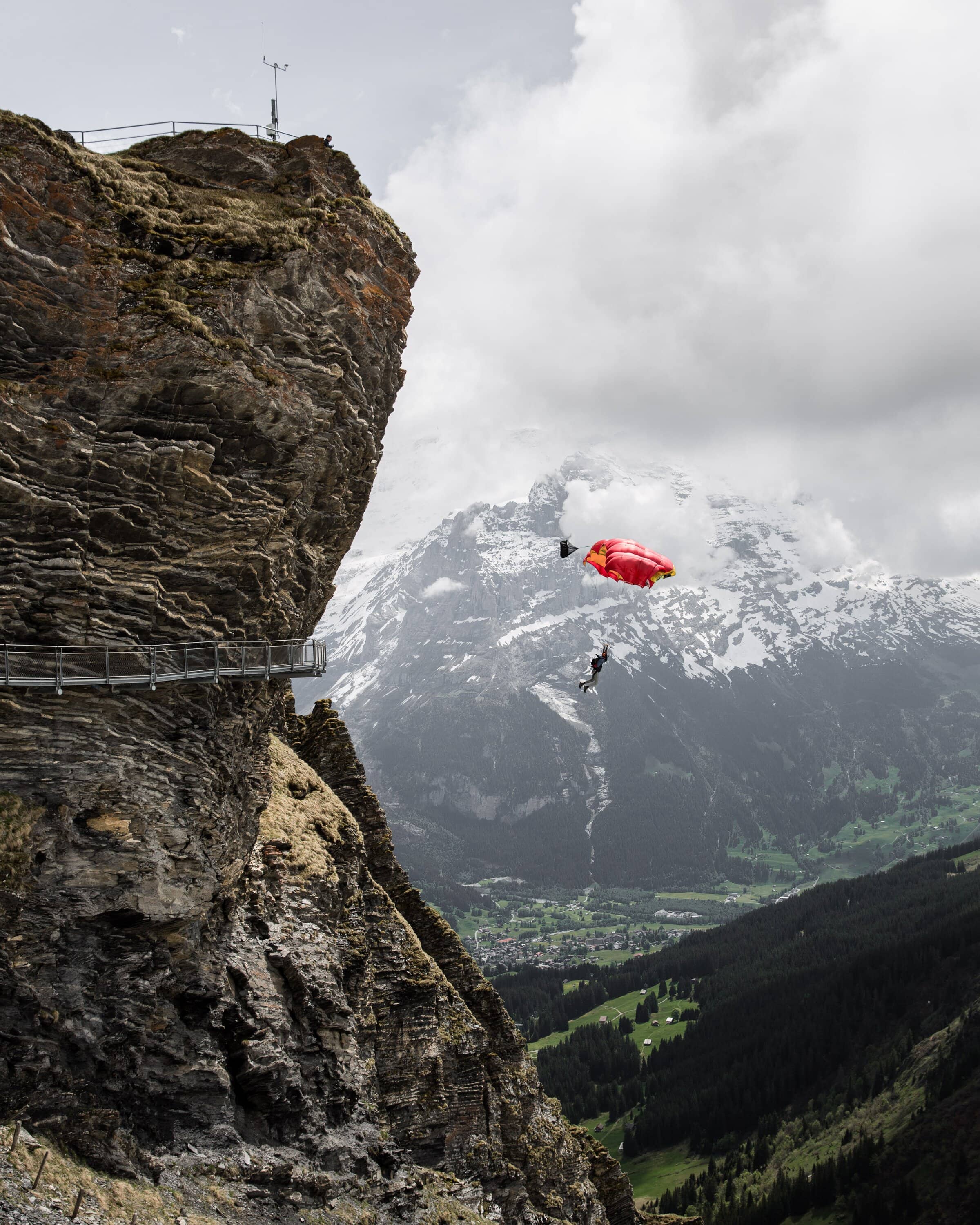 BASE Jumper springt von einem felsigen Absprungort über einem Tal
