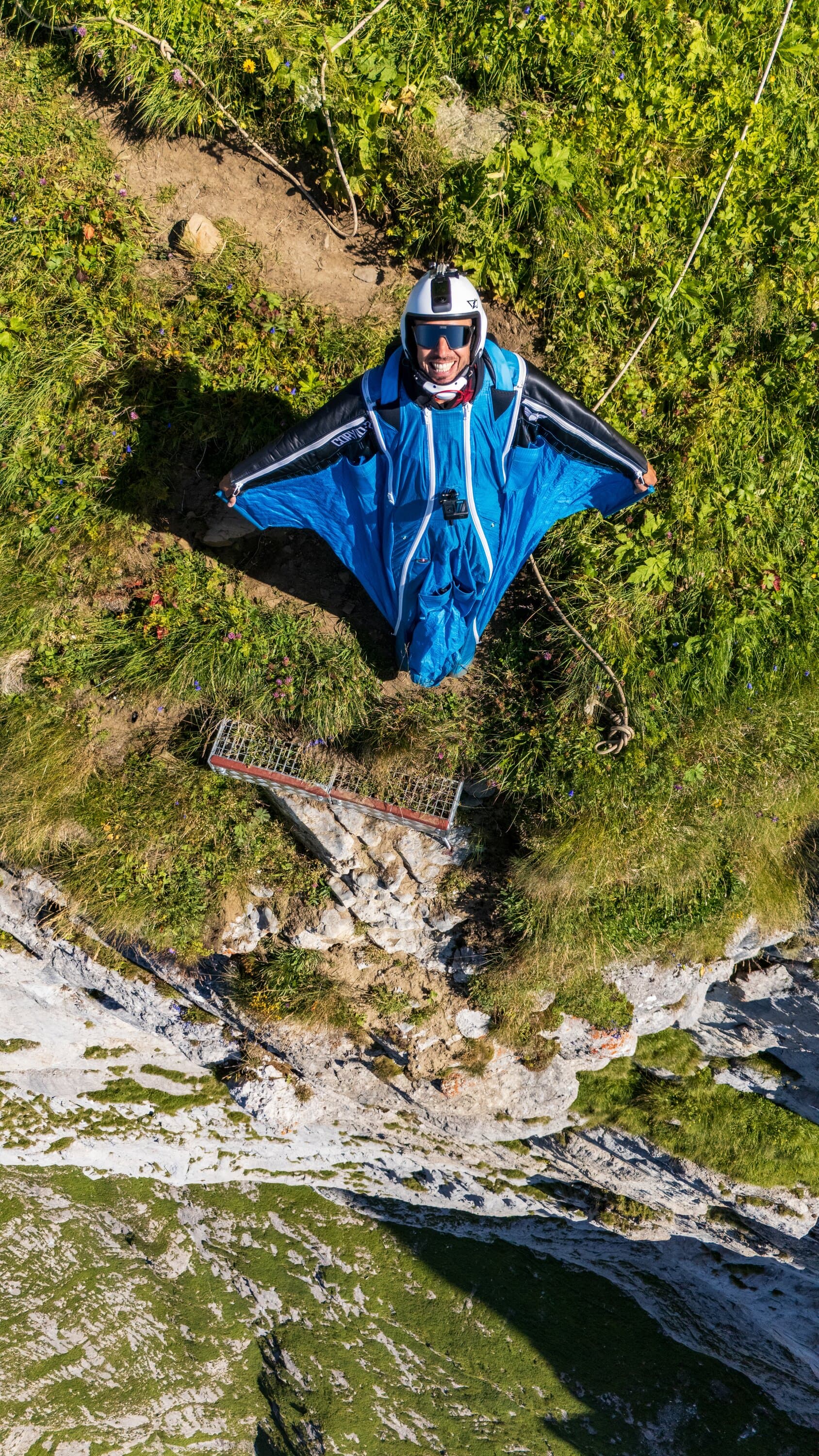 Wingsuit pilot standing on a grassy launch slope