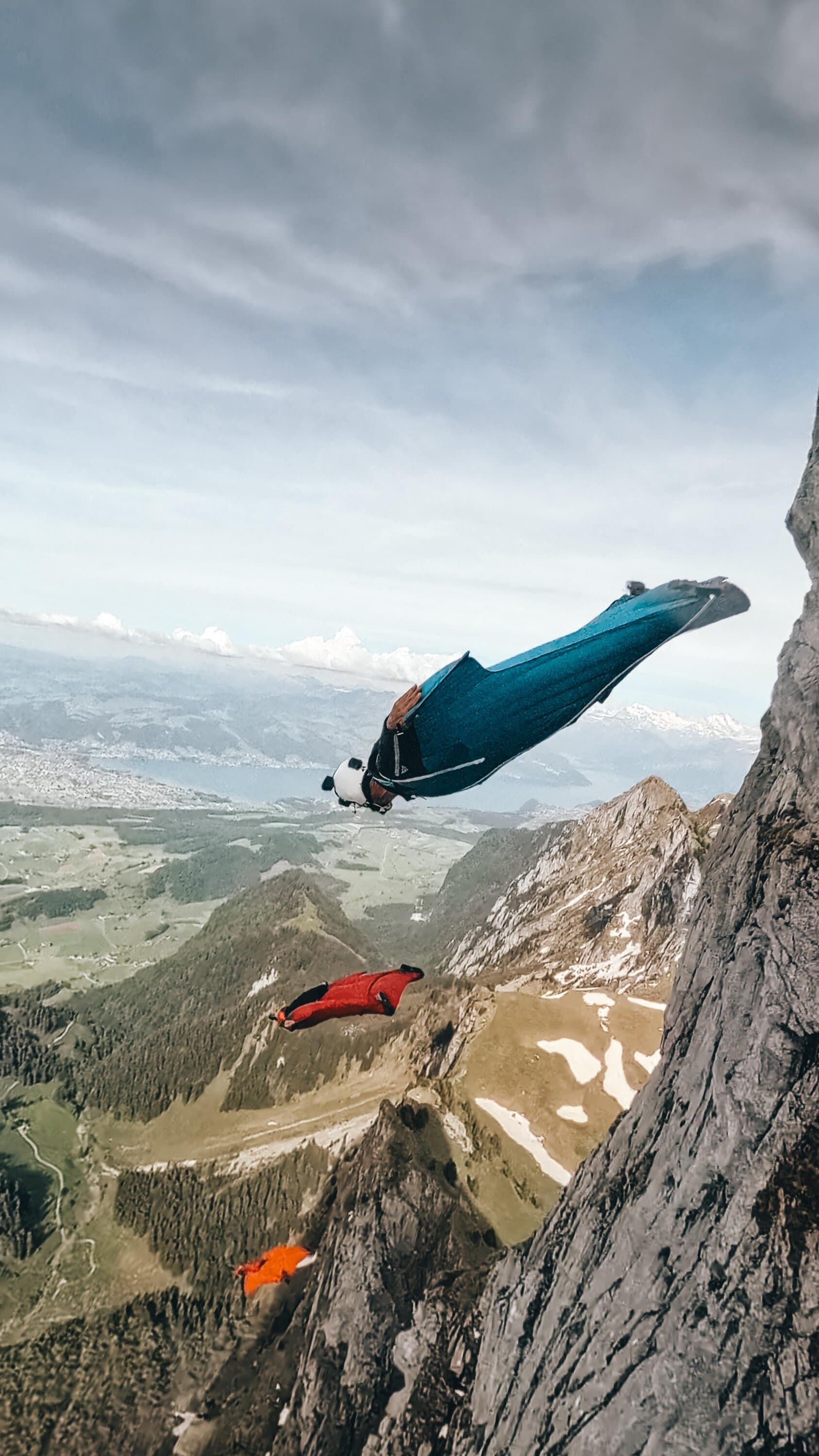 Wingsuit flyer leaving a rocky cliff above a valley