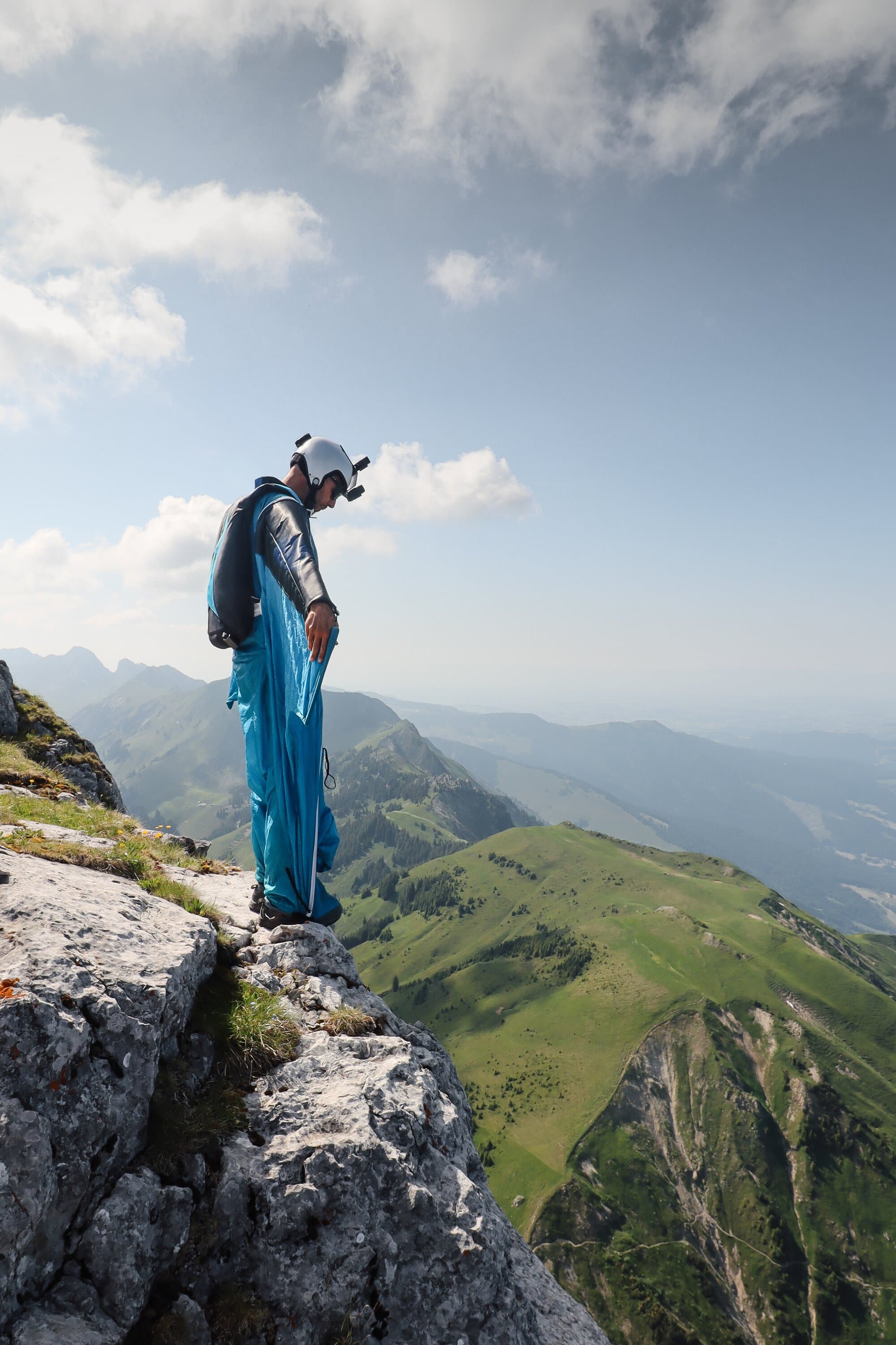 Marcel Geser standing on a cliff edge with parachute gear