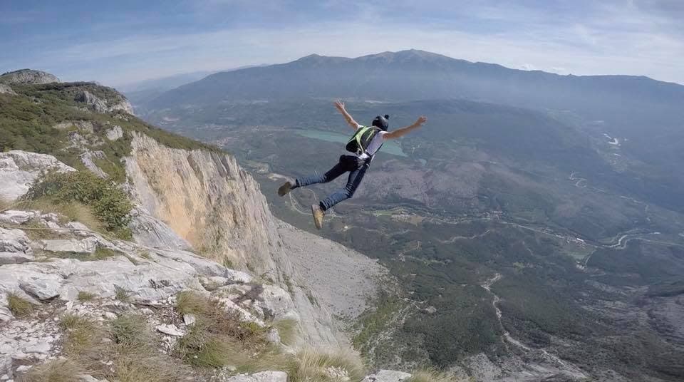 Wingsuit flyer in a yellow suit against a bright sky