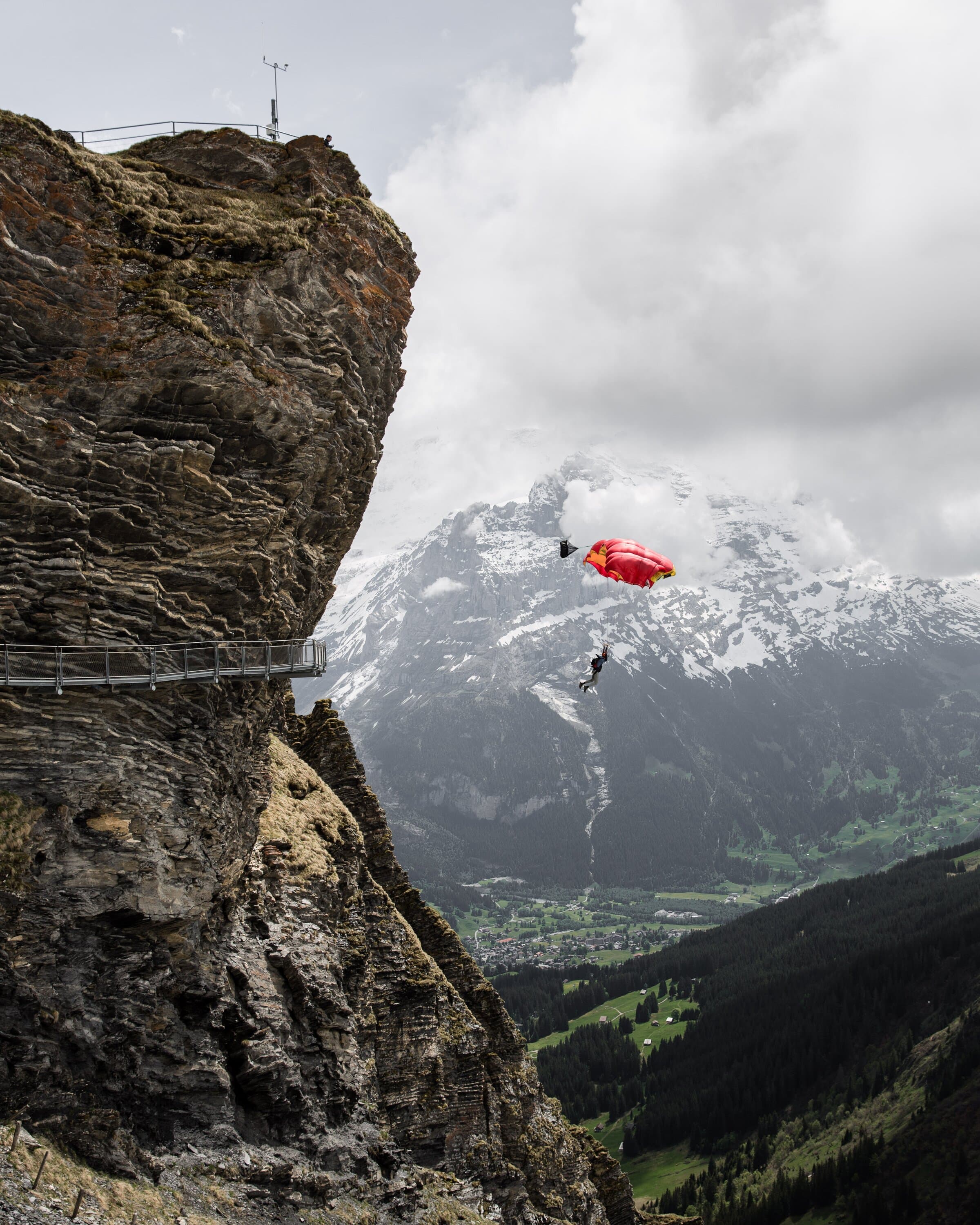 BASE canopy opening beside a cliff with snowy mountains behind