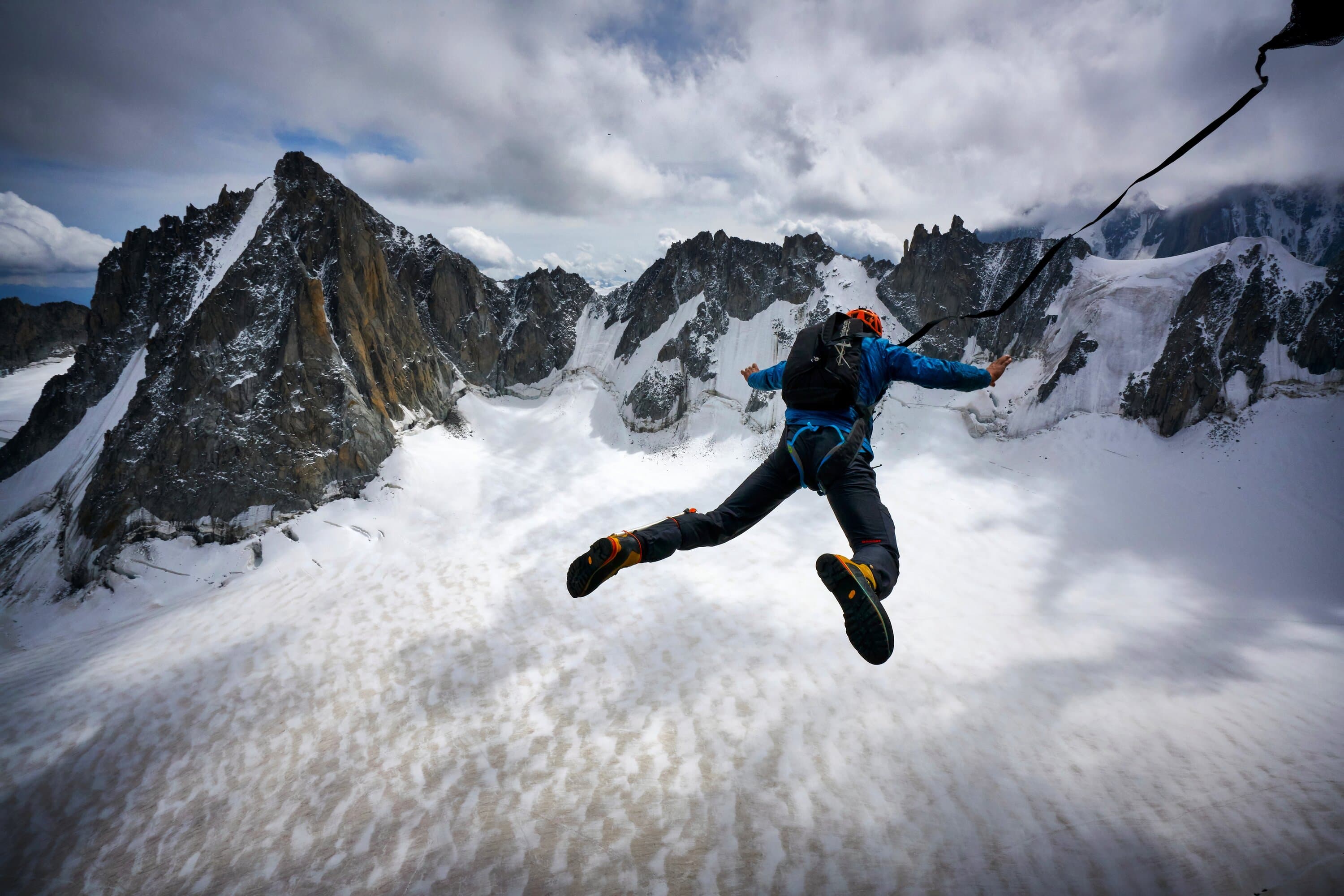 Tim Howell jumping from a snowy alpine ridge