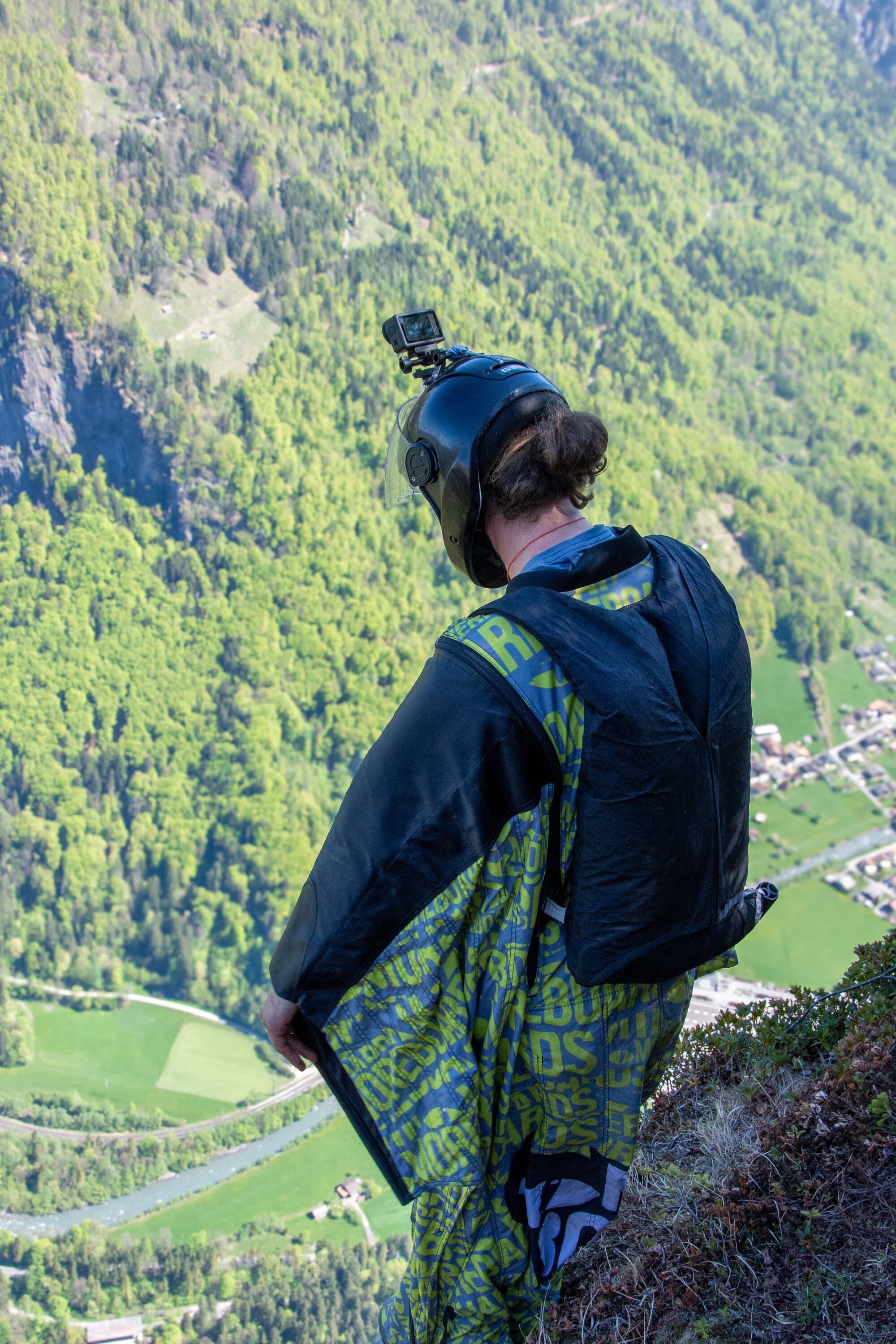 Wingsuit athlete standing above a valley during documentary fieldwork.