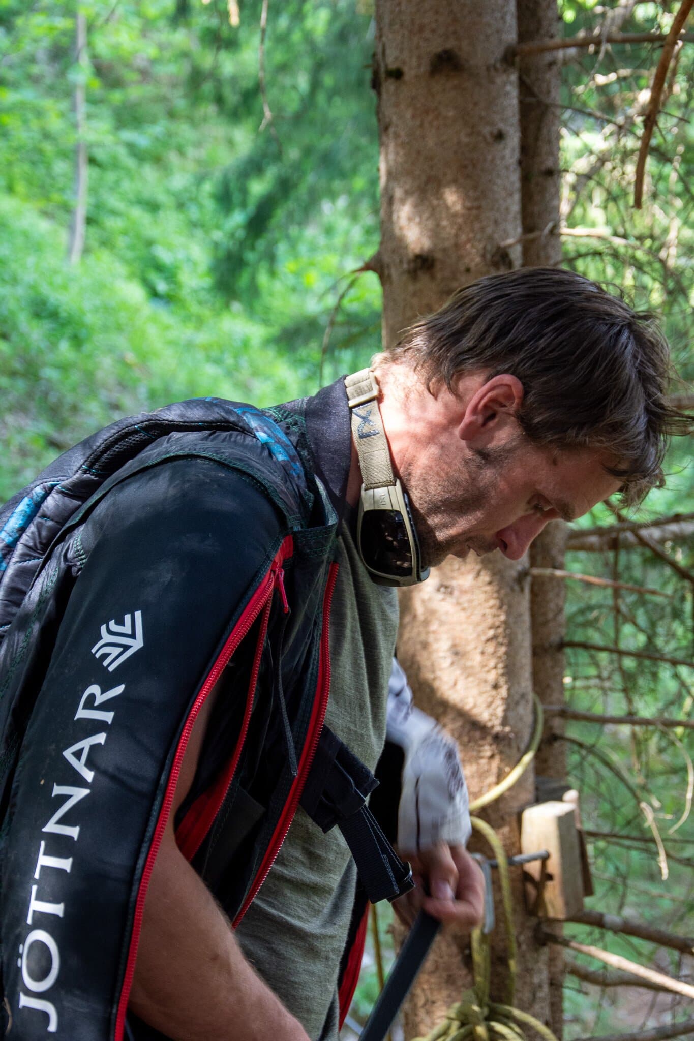 Person with a packed parachute standing above a steep valley