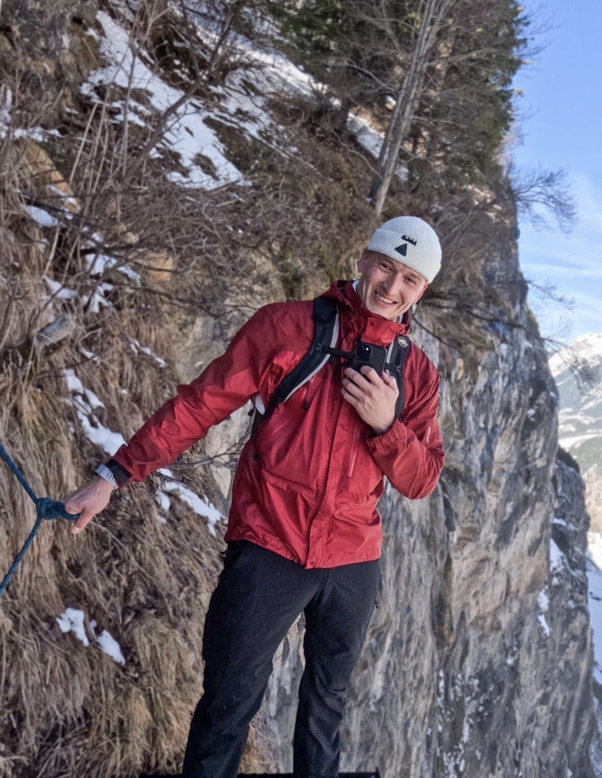 Documentary author holding a rope on a snowy cliff path