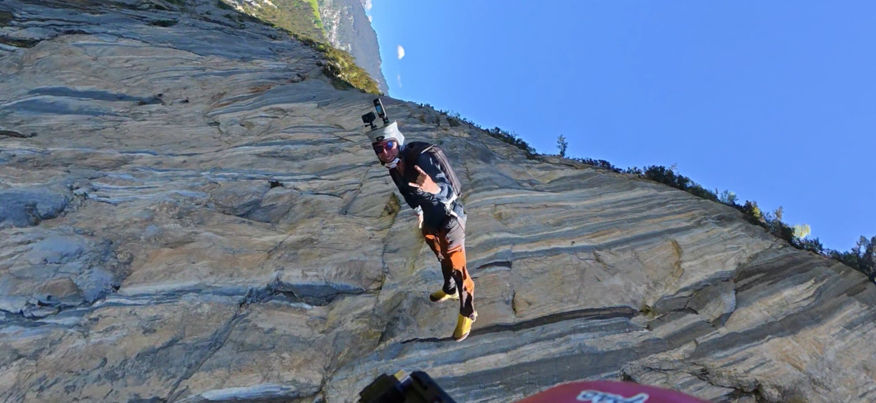 Wingsuit flyer exiting beside a rocky cliff face