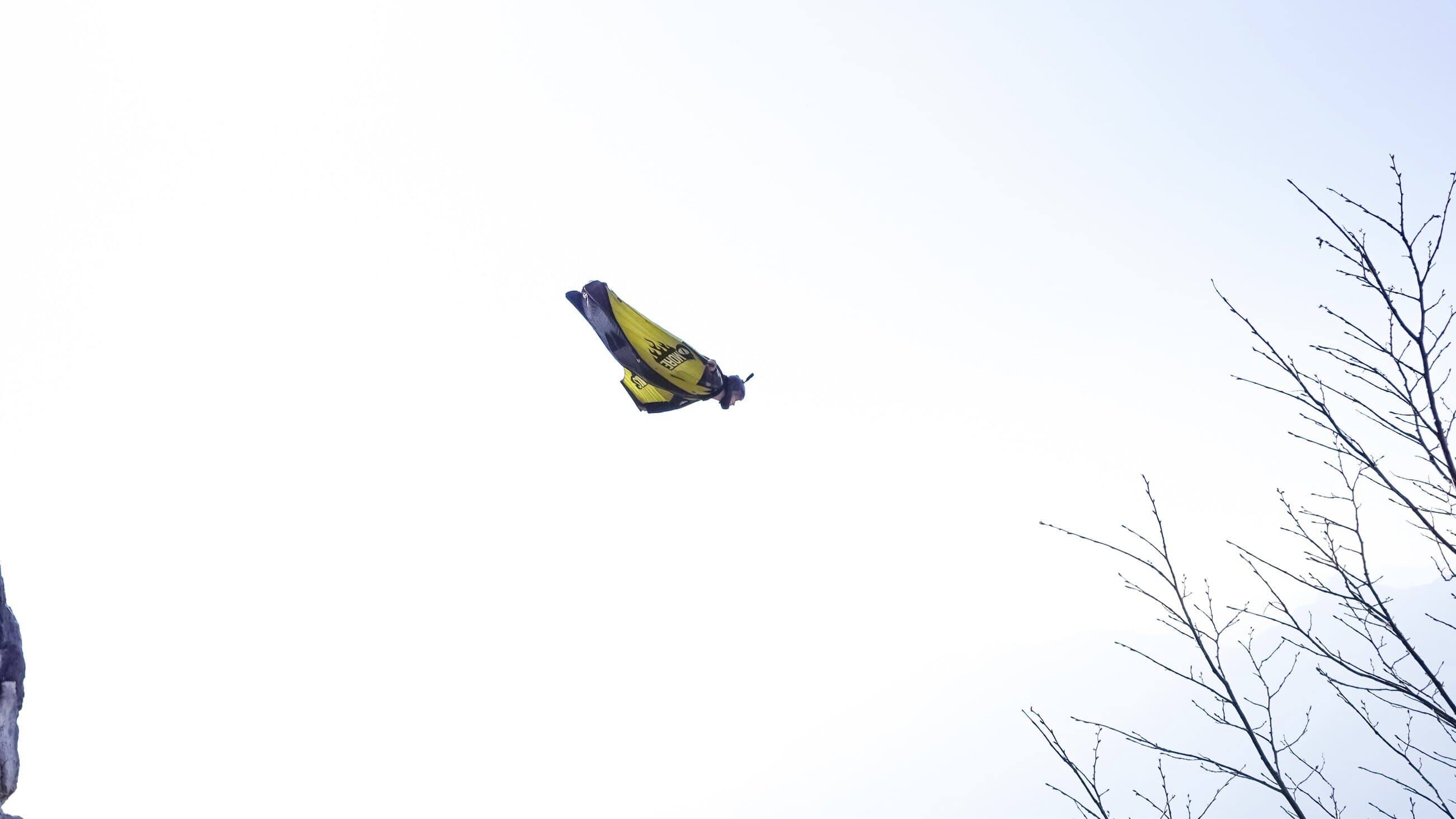 Wingsuit flyer passing through a rocky arch