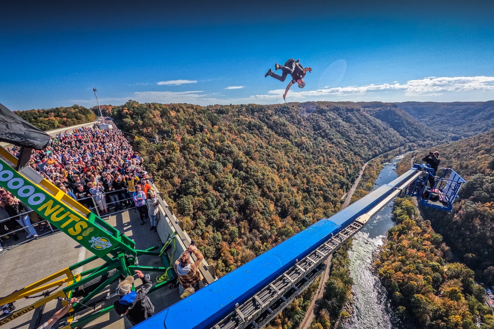BASE jumper exiting a platform above a forested valley.
